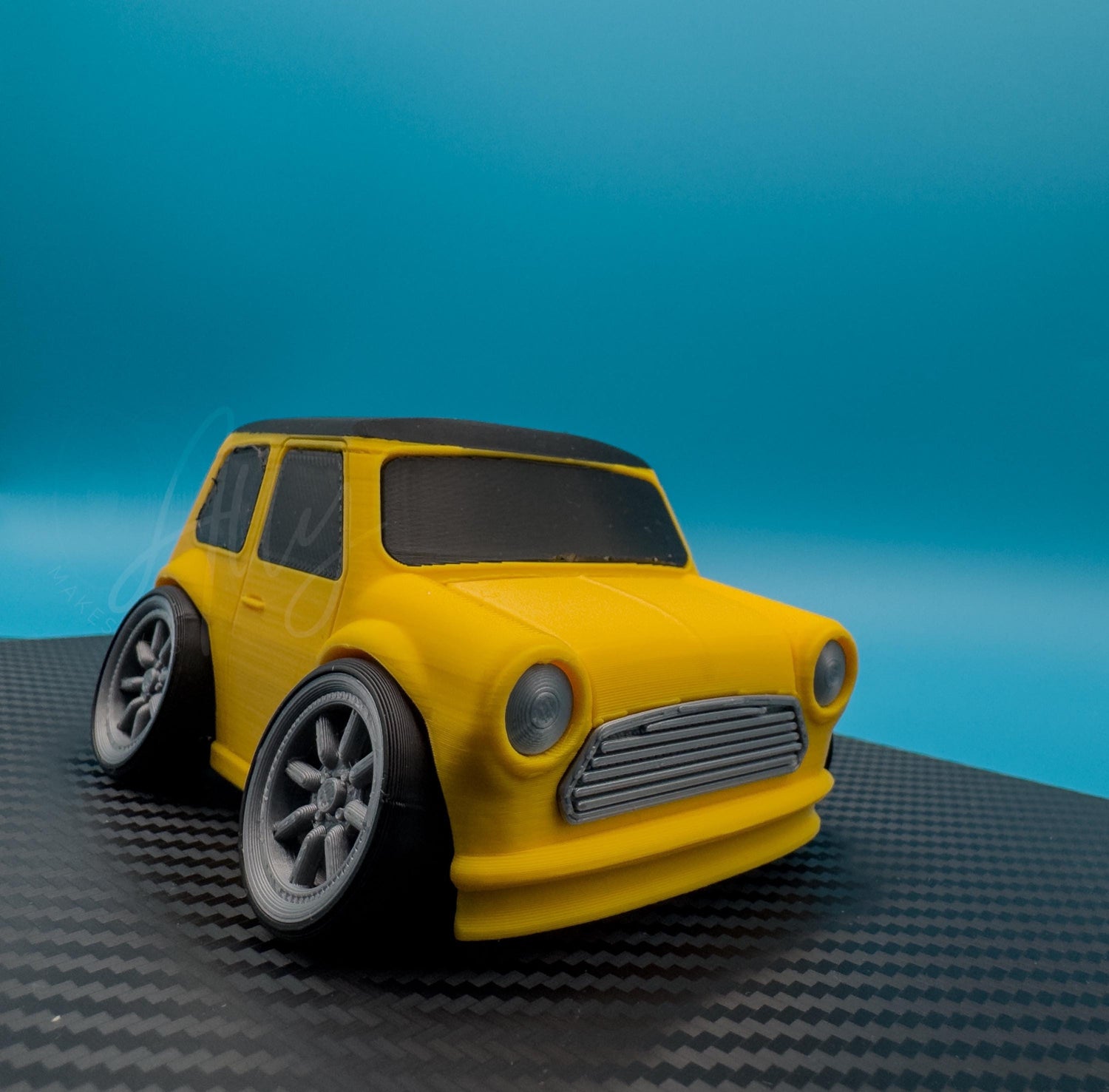 3D printed cartoon-style compact car model in yellow with black roof and silver wheels, stylised for display use.